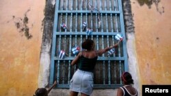 Una mujer adorna una ventana con banderas de papel en La Habana, Cuba, 2007. Reuters.