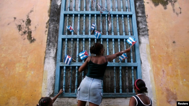 Una mujer adorna una ventana con banderas de papel en La Habana, Cuba, 2007. Reuters.