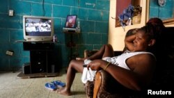 Una mujer descansa en su sofá mientras la televisión transmite una sesión de la Asamblea Nacional.