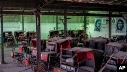 Los carros de caballos que solían dar paseos a los turistas permanecen inactivos en el garaje de una cooperativa donde los murales del difunto líder Fidel Castro y el héroe revolucionario Ernesto "Che" Guevara cubren las paredes en La Habana, Cuba, el 24 de febrero de 2021.