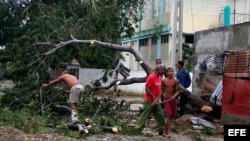 Varias personas talan árboles derribados por el huracán Sandy en el poblado de Caimanera, en la provincia de Guantánamo (Cuba).