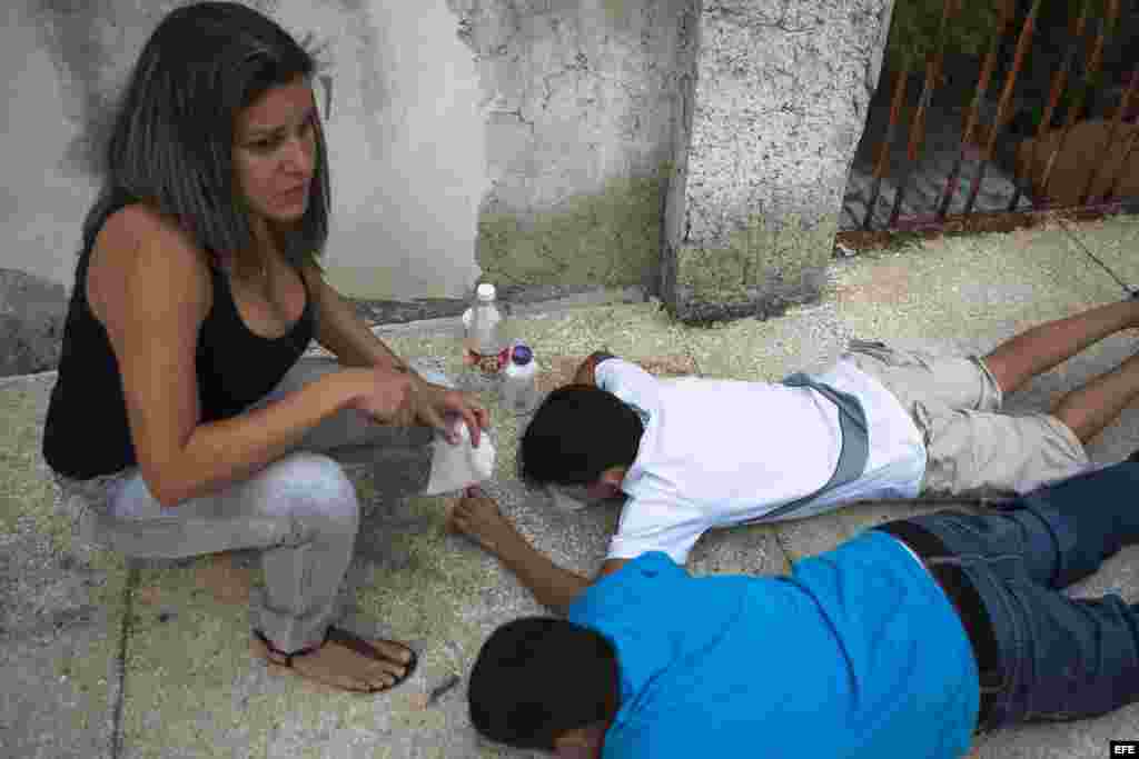 Una mujer y dos niños se protegen de las bombas lacrimógenas cerca de la Plaza Altamira de Caracas (Venezuela).