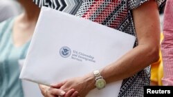 Una mujer sostiene los certificados de ciudadanía de EEUU en un sobre. Raj Mehta-USA TODAY vía Reuters.