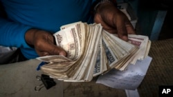 Un vendedor sostiene un fajo de pesos cubanos en un mercado de La Habana. (Ramón Espinosa/AP)