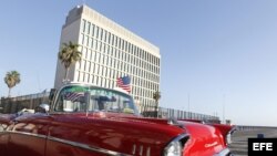 Un auto clásico pasa con una bandera de Estados Unidos frente a la embajada de ese país en La Habana.