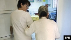 Una auxiliar acompaña al comedor a una enferma de alzheimer en el centro de día "La Pineda" en Castellón. 