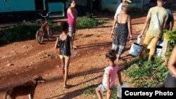 Pobladores de Güira de Melena succionan el agua de una tubería rota y la cargan en cubos hasta su residencia.