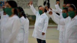Médicos cubanos alzan sus puños en ceremonia de despedida antes de su partida a Andorra, en marzo pasado. (Yamil Lage/AFP)