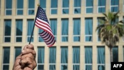 Un cubano sostiene una bandera de EEUU frente al edificio de la embajada en La Habana. 