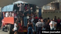 Varias personas intentan subir a un camión particular que funciona como transporte público en la ciudad de Santiago de Cuba.