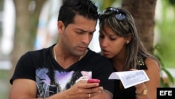 Dos jóvenes usan un teléfono móvil hoy, miércoles 9 de abril de 2014, en La Habana (Cuba)