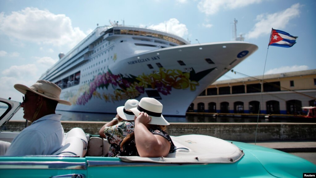 Turistas pasean en un convertible cerca de la terminal de cruceros.