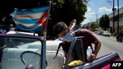 Un empleado de una compañía privada desinfecta un auto clásico en una calle de la Havana Vieja. (YAMIL LAGE/AFP)