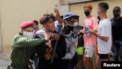 Policías vestidos de civil detienen a un menor durante protestas el 11 de julio de 2021. REUTERS / Stringer