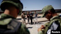 Un agente del Instituto Nacional de Inmigración (INM) habla con cubanos luego de ser detenidos por la Guardia Nacional de México mientras intentaban cruzar ilegalmente la frontera entre los Estados Unidos y México, en Ciudad Juárez. Foto Archivo