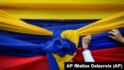 Un partidario de la oposición sostiene una tela con los colores de la bandera venezolana antes de un mitin con el líder opositor Juan Guaidó en Caracas, 11 de enero de 2020. Foto: AP /Matias Delacroix.