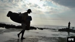 Archivo. Un pescador se dirige hacia el mar con sus utensilios de trabajo en una de las costas del litoral norte habanero.
