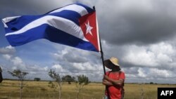 Un hombre sostiene una bandera cubana.