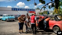 Cubanos descargan en sus autos alimentos y otros productos adquiridos en un mercado en dólares en La Habana.