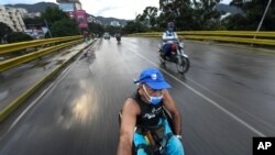 Manuel Mendoza viaja en su silla de ruedas agarrándose a la parte trasera de una motocicleta en el barrio La Paz de Caracas, el 9 de noviembre de 2020. (Matías Delacroix/AP).