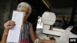 Una anciana muestra su libreta de racionamiento en una bodega de La Habana (Cuba). EFE/Alejandro Ernesto
