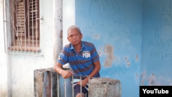Walfrido Rodríguez Piloto posa junto a carteles antigubrnamentales en los muros de su vivienda. (Tomado de un video de CubaNet)