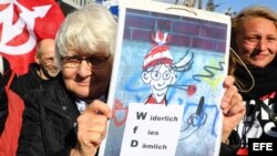 Una mujer muestra un cartel en el que se lee "Asqueroso, repugnante, estúpido" refiriendose a la organización de extrema derecha "Nosotros por Alemania".