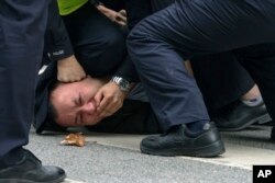 Policías arrestan a un manifestante durante las protestas de este fin de semana en Shanghai, China. (AP Photo)