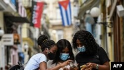 Jóvenes cubanos tratando de acceder a Internet. (Photo by YAMIL LAGE / AFP).
