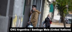 Un hombre habla por teléfono usando una pantalla para protegerse del COVID-19 en Buenos Aires, Argentina. Foto: ONU Argentina / Santiago Mele.