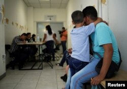 Un hombre y su hijo pequeño, procedentes de El Salvador, esperan su turno para presentar su aplicación de asilo.