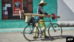 Un hombre camina con su bicicleta de la mano por una calle de Santa Clara.