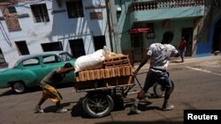 Residentes transportan bloques en una carretilla por una calle de la La Habana. 