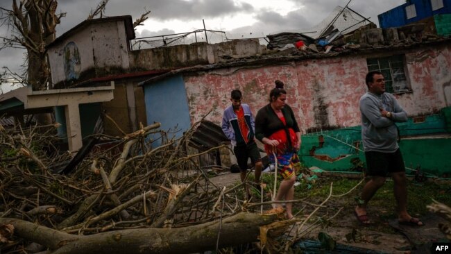 Residentes del barrio de Regla caminan sobre los escombros en busca de sus pertenencias. 