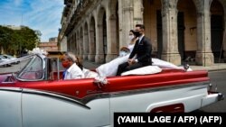 Una pareja de recién casados se pasea por La Habana en un auto de alquiler. Los negocios privados se han visto muy afectados durante la pandemia en Cuba. (YAMIL LAGE / AFP)