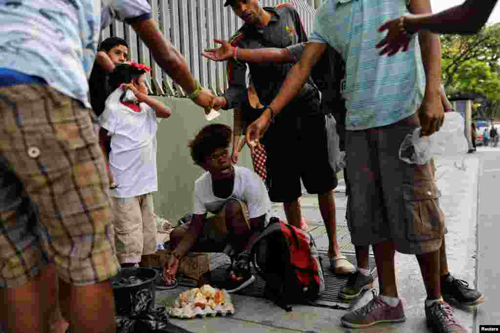 Un grupo de jóvenes comen de una torta después de encontrarla en una bolsa de basura en Caracas, Venezuela, el 27 de febrero de 2019.