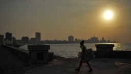 Una mujer camina con mascarilla por el malecón de La Habana.
