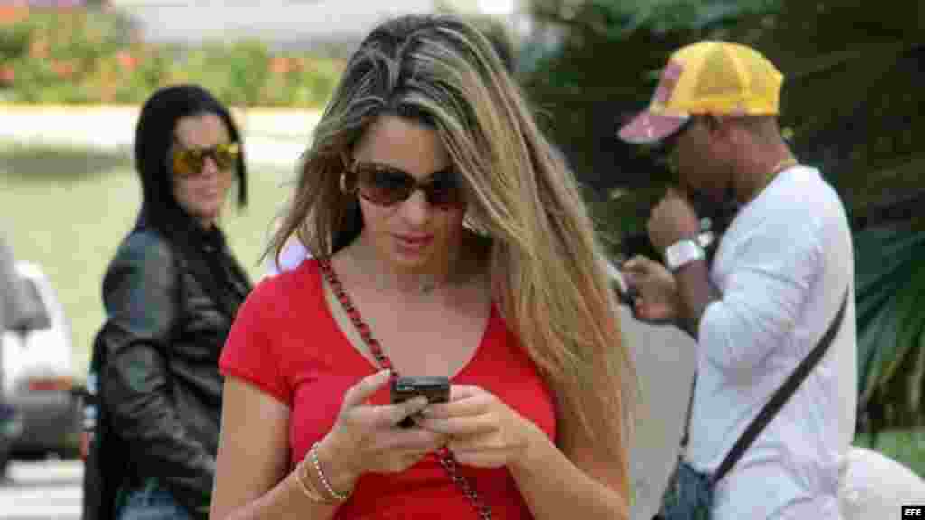 Una joven revisando su teléfono celular en una calle de La Habana.