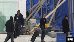 Un hombre (2º dcha), que pudiera ser uno de los investigadores internacionales, carga con una maleta en el mausoleo de Yaser Arafat en Ramala (Cisjordania).