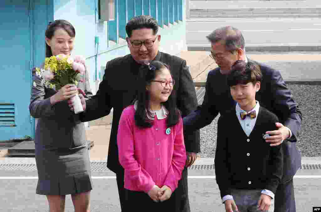 Kim Yo Jong, con un ramo de flores, junto a su hermano Kim Jong Un y el presidente de Corea del Sur, Moon Jae-in, posan con niños después de reunirse en la zona desmilitarizada de Panmunjom, el 27 de abril de 2018. (Korea Summit Press Pool/ AFP)