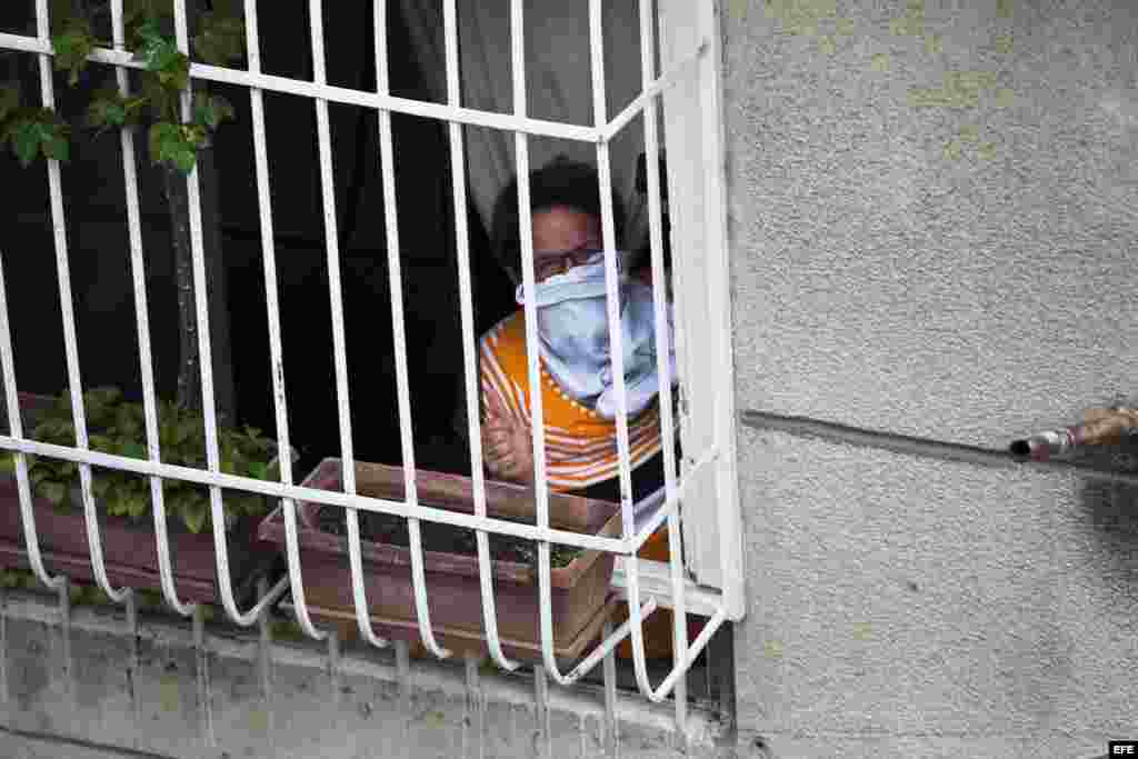 Una mujer observa desde una ventana cerca de la Plaza Altamira de Caracas (Venezuela). Los vecinos de la céntrica plaza de Chacao viven a diario las consecuencias de los enfrentamientos entre opositores y las fuerzas del orden.