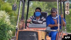 Dos cubanos viajan el martes en tractor por una calle de La Habana (Yamil Lage/AFP).