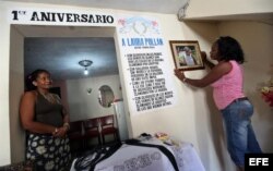 Berta Soler (d), líder de las Damas de Blanco, acomoda un retrato de la fallecida Laura Pollán en la sede de ese movimiento junto a la opositora cubana Belquis Núñez Fajardo (i) hoy, viernes 12 de octubre de 2012, en La Habana (Cuba).