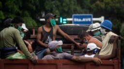 Trabajadores con máscaras protectoras por el coronavirus viajan en un camión en La Habana. (AP/Ramon Espinosa)
