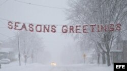 Un letrero de "Felices Fiestas" es cubierto por la nieve en una calle de Beaver Dam, estado de Wisconsin (EEUU).