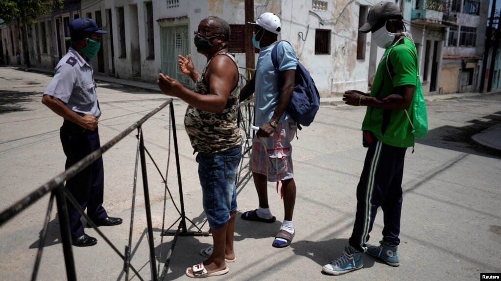 En esta foto tomada el 8 de julio en la barrera de acceso a un barrio habanero, un policía habla con personas que se disponían a pasar a una zona restringida (Foto: Alexandre Meneghini/Reuters).