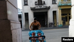 Una mujer lleva en coche a dos bebés por una calle de La Habana, que sigue siendo el epicentro de la pandemia en Cuba. REUTERS/Stringer