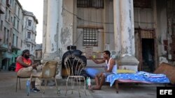 Dos hombres cuya vivienda fue severamente afectada por el huracán Irma conversan junto a sus pertenencias el jueves 21 de septiembre de 2017, en el malecón de La Habana (Cuba).