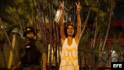 Una mujer hace un llamado a la paz mientras protestantes se enfrentan con miembros de la Guardia Nacional Bolivariana (GNB.