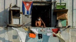 Un hombre con una máscara protectora desde su balcón en La Habana. (YAMIL LAGE / AFP)
